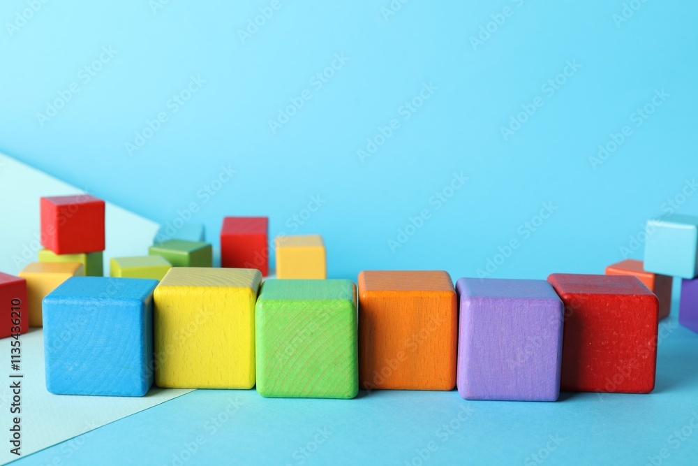 Colorful wooden cubes on light blue background, space for text Colorful wooden cubes on light blue background, space for text