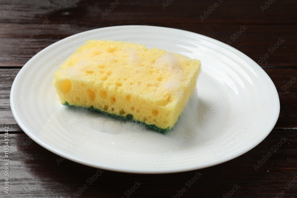 Yellow sponge with foam and plate on wooden table, closeup Yellow sponge with foam and plate on wooden table, closeup