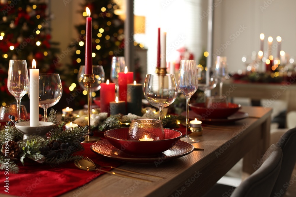 Christmas table setting with stylish dishware, glasses and burning candles in festive decorated room Christmas table setting with stylish dishware, glasses and burning candles in festive decorated room