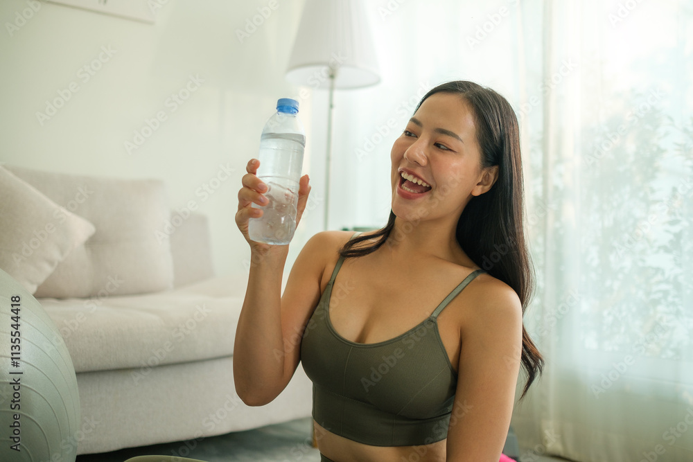 Smiling fit woman holding a bottle of water taking a break during her workout, sitting on the floor in a relaxed position. Smiling fit woman holding a bottle of water taking a break during her workout, sitting on the floor in a relaxed position.