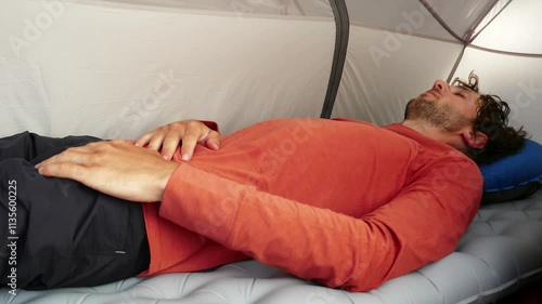 a man sleeps on an inflatable mat and pillow in a tourist tent
