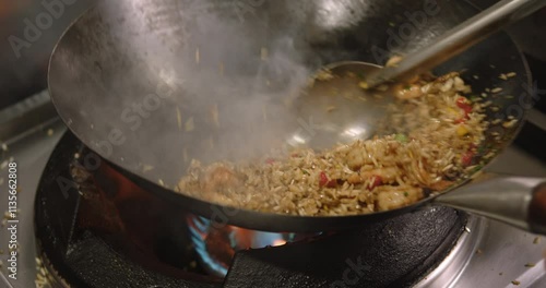 Close-up of a chef cooking Peruvian shrimp fried rice in a big pan