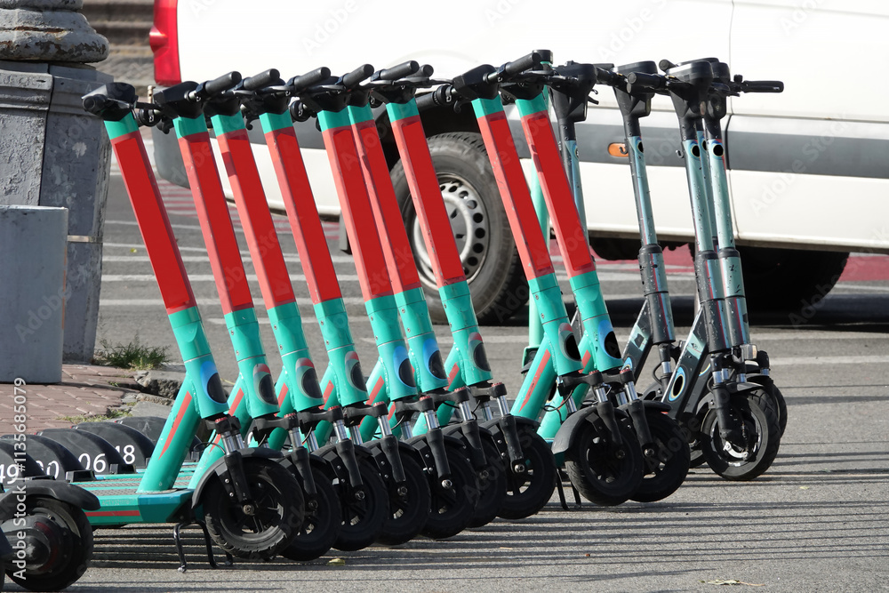 Electric scooters stand in a row