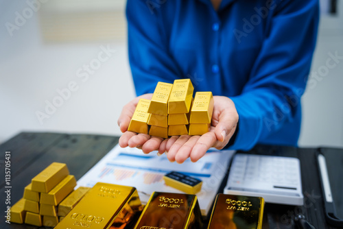 An Asian businesswoman sits at her desk analyzing gold bar prices, buying and selling gold, trading gold stocks, monitoring charts, and studying currency trends in an uptrending stock market. photo