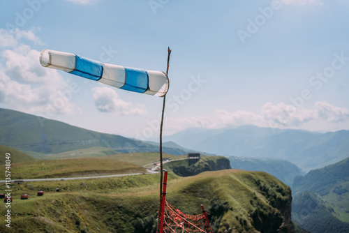 A wind cone with white and blue stripes on the background of a mountain landscape. An outbuilding on the background of a mountain range. The wind in the mountains. Wind direction detection device photo