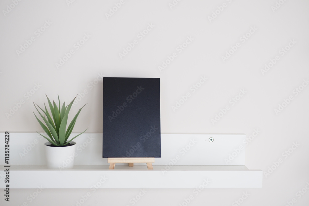 Stylish Minimalist Home Decor Featuring a Black Notebook and a Green Plant Stylish Minimalist Home Decor Featuring a Black Notebook and a Green Plant