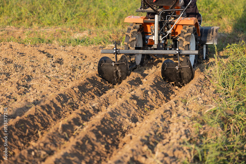Fototapeta Mini Tractor with attachments to make the furrows in garden.