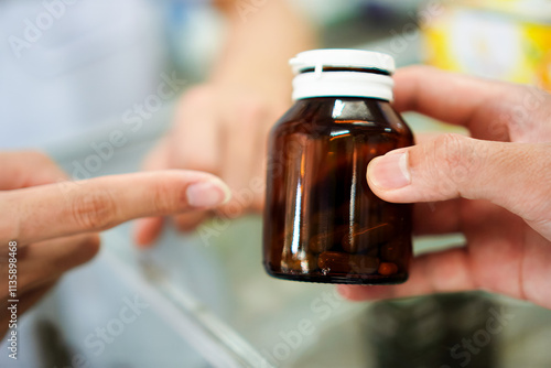 Fotografi Photo of a pharmacist instructing a patient on how to store tablets in an opaque container in a pharmacy, Thailand