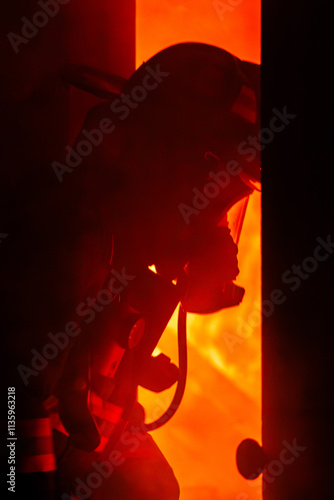 Silhouette of a firefighter entering a room with fire in the background.