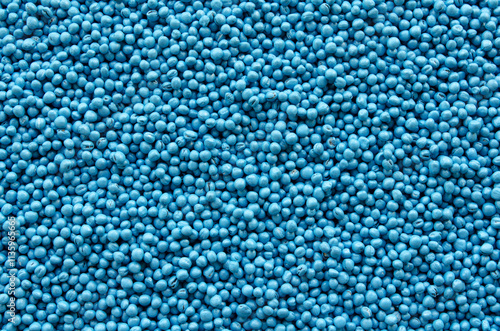 Treated rapeseed with blue coating, background, texture, top view. Encrusted rapeseed ready for sowing. Background of treated rapeseed, blue color, texture, top view.