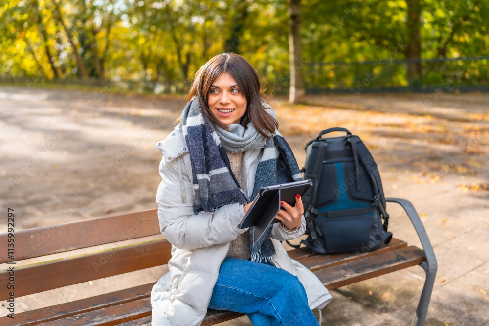 Woman using digital tablet sitting on a park bench