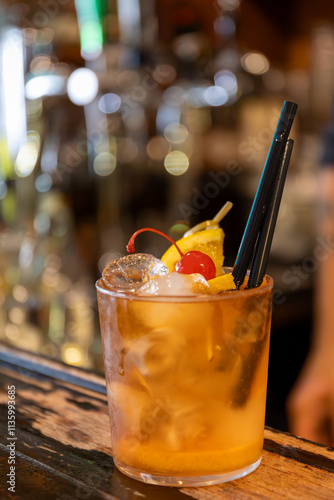 Close up shot from above of a cocktail on the counter of an aperitif bar in Milan, Italy. Red sweet cherry and a slice of orange in the drink. Aperitif, drinking.