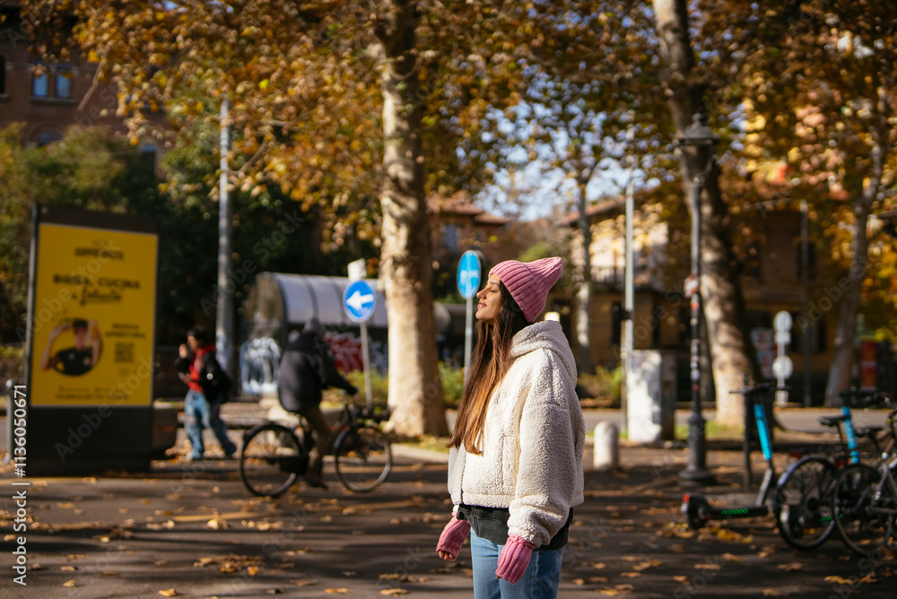 Fototapeta premium A young woman enjoys a sunny autumn day, walking through the city and soaking in the vibe