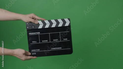 Movie Clapper board clapped by Hands on green screen camera background. Filmmaker hit film slate on green camera frame. Clapperboard Chroma key suit shooting. Green screen composite video production.