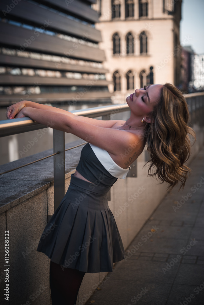 Fototapeta premium Kobieta oparta o barierkę odchylona do tyłu luźno puszczone włosy