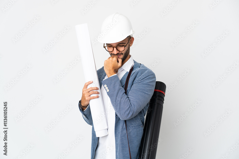 Young architect man with helmet and holding blueprints isolated on white background having doubts Young architect man with helmet and holding blueprints isolated on white background having doubts