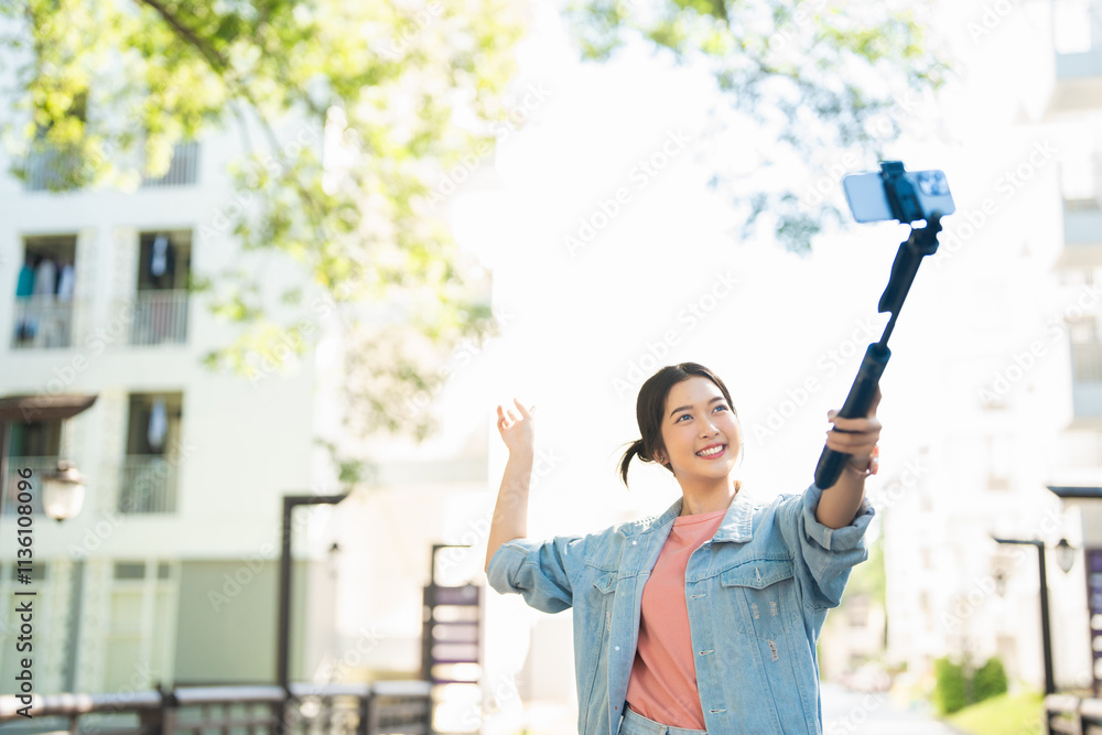 Tourists in the city taking selfies on university street. Asian girl taking selfies while walking on the street in summer happily with her mobile phone. Travel and summer vacation lifestyle concept. Tourists in the city taking selfies on university street. Asian girl taking selfies while walking on the street in summer happily with her mobile phone. Travel and summer vacation lifestyle concept.