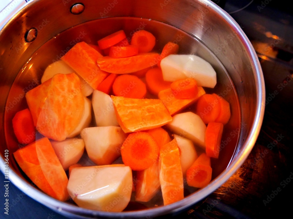 A pot full of cuts sweet potato, carrots and potatoes ready to be cook A pot full of cuts sweet potato, carrots and potatoes ready to be cook