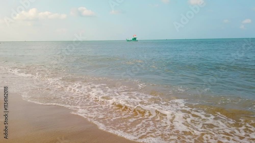 A green fishing boat with Vietnamese flags bobs on the waves anchored on a sunny day