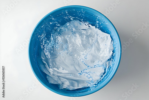 White clothes submerged in a blue basin with splashing water. photo