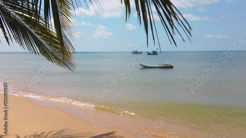 A fishing boat sails between anchored other boats off the coast of a Vietnamese island