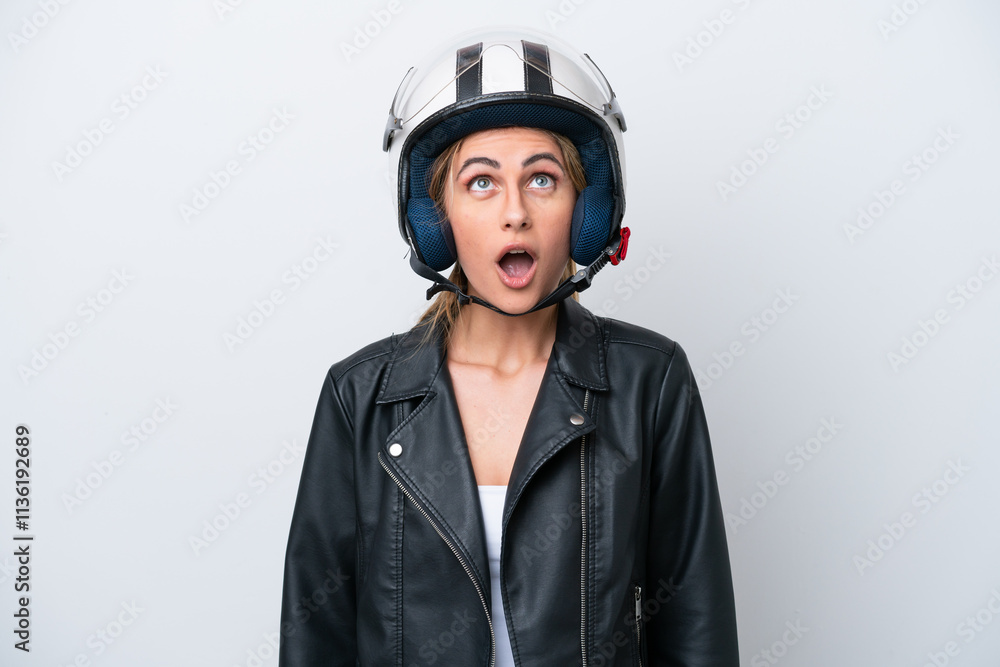 Young caucasian woman with a motorcycle helmet isolated on white background looking up and with surprised expression Young caucasian woman with a motorcycle helmet isolated on white background looking up and with surprised expression