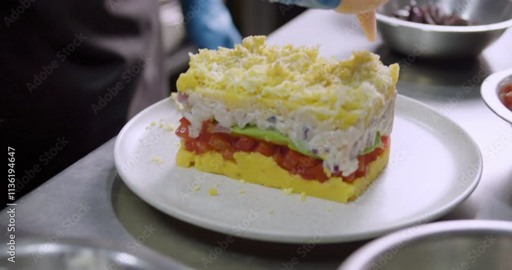 Fresh prepared Peruvian Causa on a white plate over a kitchen metal table Fresh prepared Peruvian Causa on a white plate over a kitchen metal table