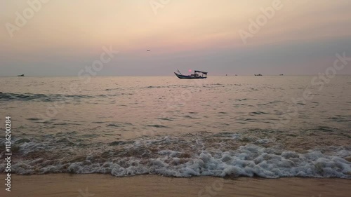 Silhouette of a boat against a sunset and pink sky over the sea