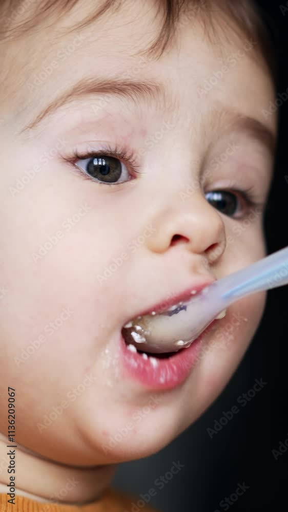 Portrait of a lovely toddler being fed from spoon. Mother giving a spoon full of cottage cheese to her son and he takes it willingly. Close up. Vertical video Portrait of a lovely toddler being fed from spoon. Mother giving a spoon full of cottage cheese to her son and he takes it willingly. Close up. Vertical video