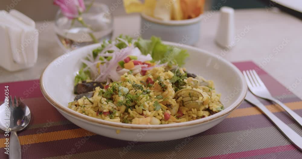 serving fresh and delicious Peruvian Seafood Rice on restaurant's table, with tableware around serving fresh and delicious Peruvian Seafood Rice on restaurant's table, with tableware around