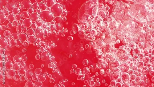 Bubbles forming in a vibrant red liquid during a refreshing drink preparation in a kitchen setting
