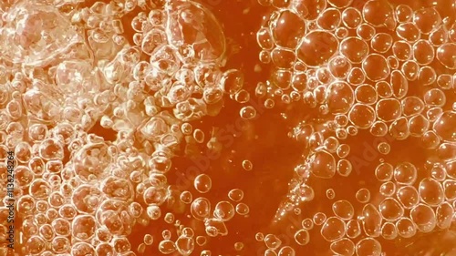 Bubbles rising in a fizzy drink, showing the effervescent texture and vivid orange color
