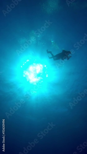 Wallpaper Mural Vertical video, Bottom-up view  on silhouette of one scuba diver swims in blue depths of the ocean illuminated by sunrays, Contre-jour, Slow motion of diver swims on the deep in sunlight, Back light Torontodigital.ca