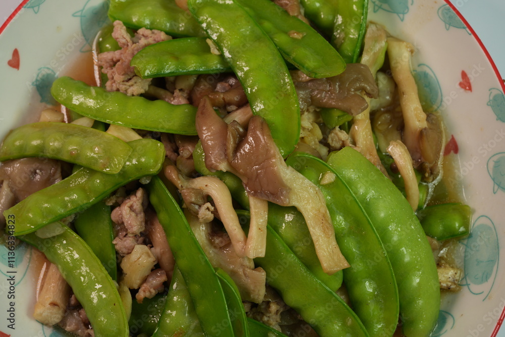 Stir-fried snow peas with oyster mushrooms and small pieces of pork. Thai people love to eat it. Stir-fried snow peas with oyster mushrooms and small pieces of pork. Thai people love to eat it.