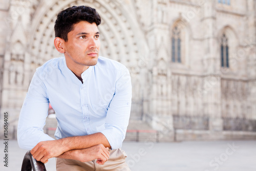 Young European guy in blue shirt walking around city photo