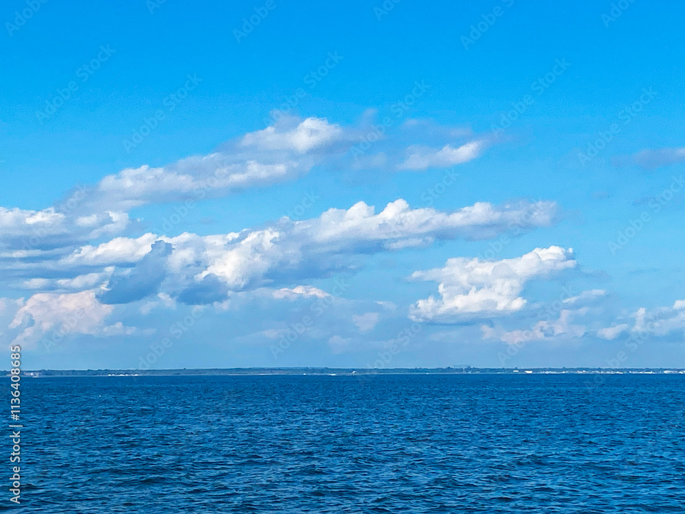 Calm Blue Ocean Under Bright Cloudy Sky During Midday With Distant Land on the Horizon Calm Blue Ocean Under Bright Cloudy Sky During Midday With Distant Land on the Horizon