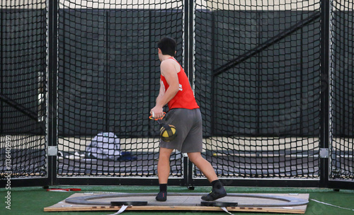 Young Athlete Throws the weight Indoors at a copmetition photo