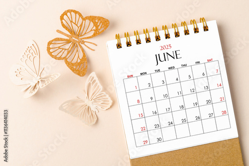 June 2025 desk calendar for the organizer to plan and reminder and butterfly paper on yellow. photo