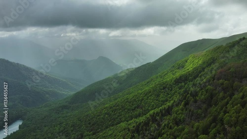 Aerial view of dark clouds and sun rays over summer green mountains landscape, Montenegro, 4k