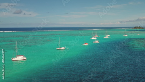 Aerial drone view of sailboats yachts and catamarans moored in shallow, turquoise water near a tropical island, creating a serene and idyllic scene, relaxing summer holiday vacation or getaway concept