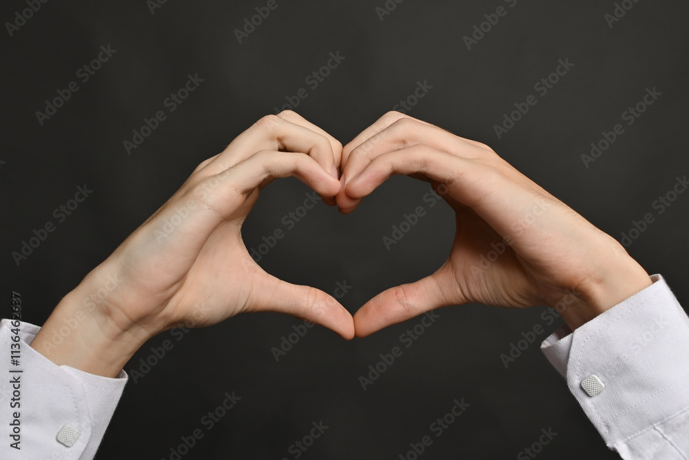 Obraz premium gesture of love, hands show heart on grey background. The gesture shows symbol of romance, close-up