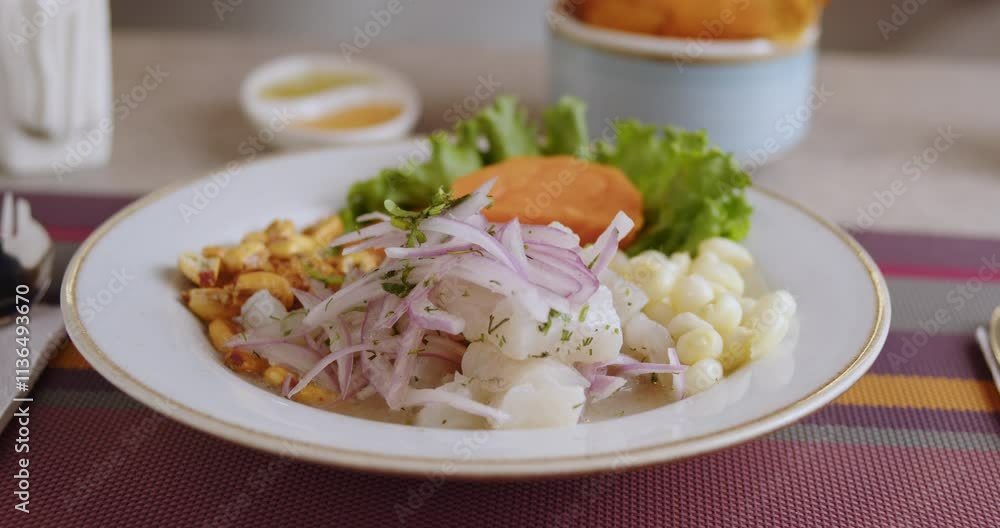 white plate contains fresh Peruvian Ceviche, sits on a table with tableware in restaurant white plate contains fresh Peruvian Ceviche, sits on a table with tableware in restaurant
