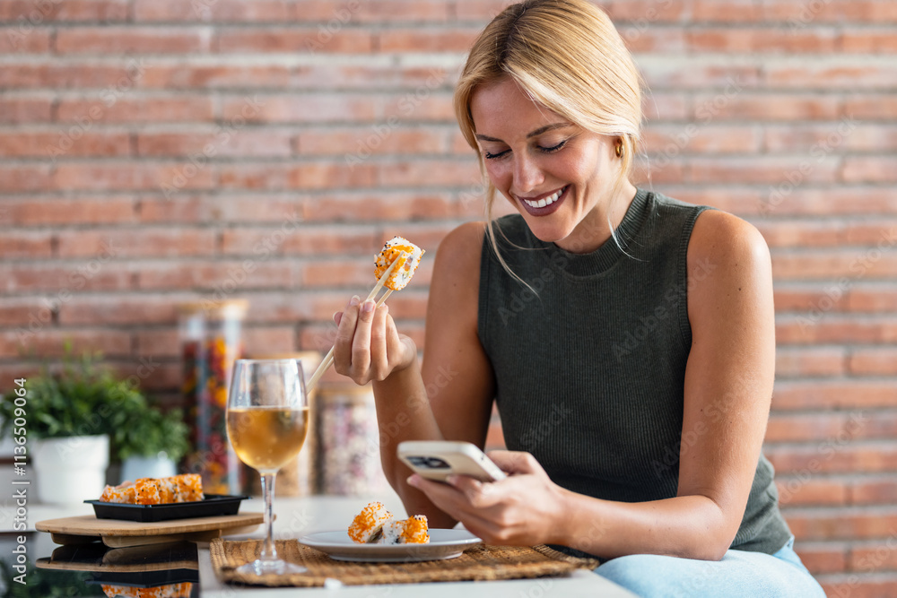 Pretty young woman eating sushi while using smartphone in the kitchen at home Pretty young woman eating sushi while using smartphone in the kitchen at home