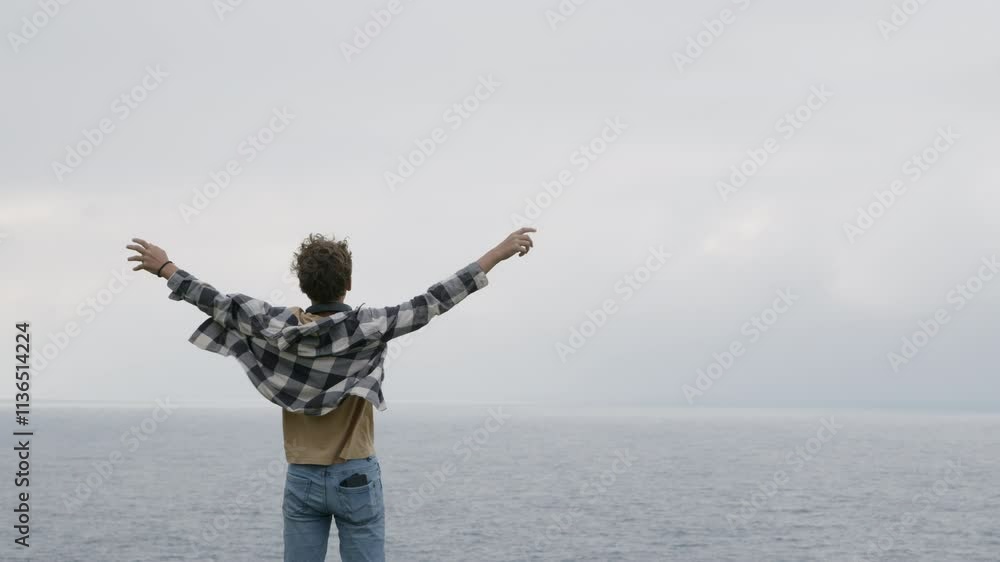 Teenager celebrating freedom with open arms in front of the ocean, embracing the beauty of nature and the joy of travel Teenager celebrating freedom with open arms in front of the ocean, embracing the beauty of nature and the joy of travel