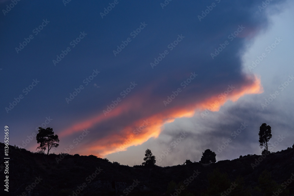 A breathtaking view of a vibrant sunset sky with dramatic cloud formations, silhouetted trees, and distant hills, evoking a sense of tranquillity and awe. A breathtaking view of a vibrant sunset sky with dramatic cloud formations, silhouetted trees, and distant hills, evoking a sense of tranquillity and awe.