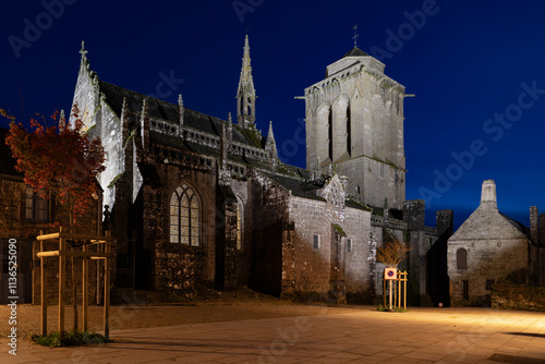 L'église de Locronan la nuit, éclairée par quelques réverbères. Le ciel bleu de l'heure bleue enveloppe l'ensemble, créant une ambiance sereine et mystérieuse.