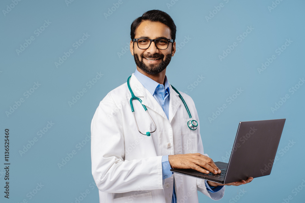 Smiling Indian man, doctor wearing stylish eyeglasses, white coat and stethoscope, holding laptop Smiling Indian man, doctor wearing stylish eyeglasses, white coat and stethoscope, holding laptop