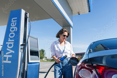 Woman holds a hydrogen fueling nozzle on a hydrogen filling station. Refueling car with hydrogen fuel photo