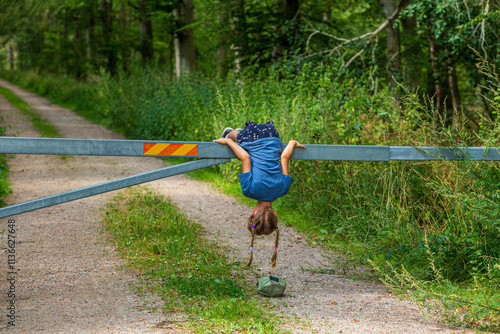 Girl loses her cap as she hangs over a road barrier