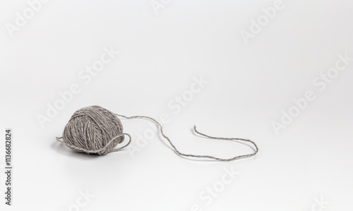 A ball of grey thread on a white surface
